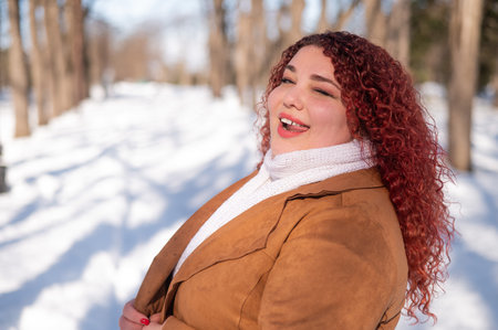 Cheerful fat caucasian woman walks in the park in winter.