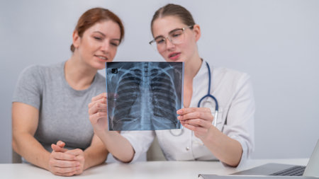 The doctor consults a caucasian woman and comments on the x-ray of the lungs.