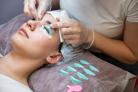 The master removes the composition for lamination from the clients eyelashes with a cotton swab. Eyelash perm procedure.の写真素材