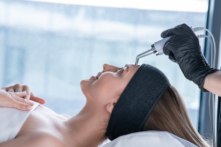 Young caucasian woman on microcurrent therapy procedure. Beauticians office.