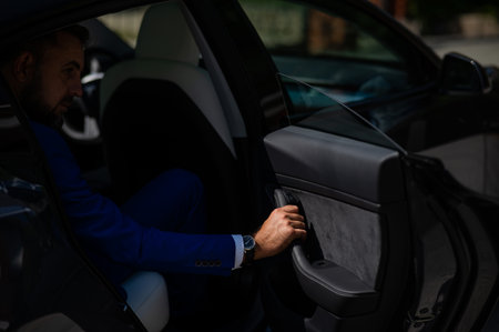 A man in a blue suit opens the car door. Close-up of a mans hand with an expensive watch.の写真素材