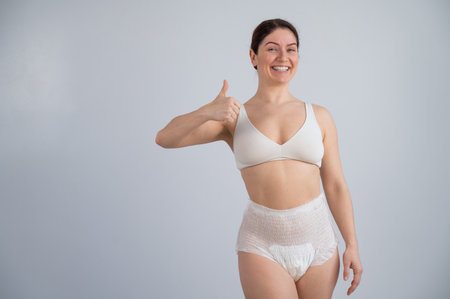 Woman in adult diapers smiling and showing thumbs up. Urinary incontinence problem.の写真素材