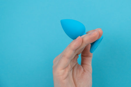 Woman holding a blue anal plug on a blue background.の写真素材