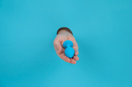 Woman holding a blue anal plug on a blue background.の写真素材