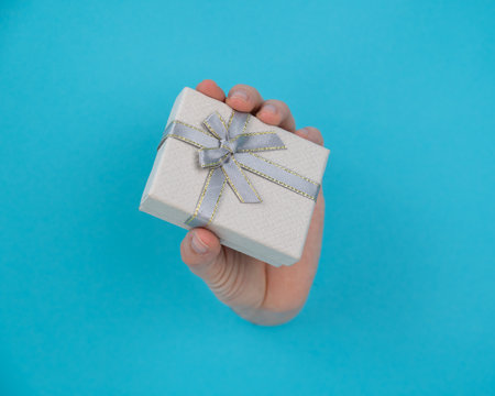 A womans hand sticks out of a blue paper background and a gift box.の写真素材