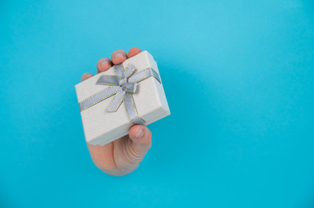 A womans hand sticks out of a blue paper background and a gift box.の写真素材