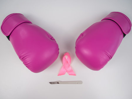 Pink boxing gloves, a surgical scalpel and a pink ribbon on a white background. The concept of fighting breast cancer.の写真素材
