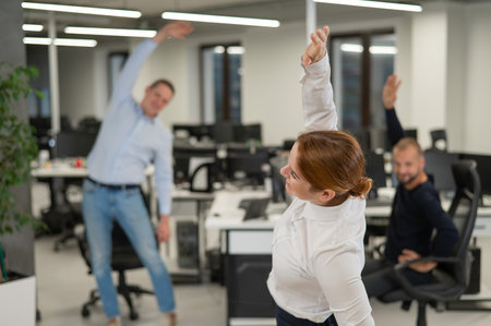 Three office workers warm up during a break. Employees do fitness exercises at the workplace.の写真素材