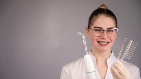 The cosmetologist doctor holds the darsonval device with different nozzles.