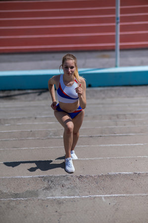Young caucasian woman running on stadium stairs outdoors.の写真素材