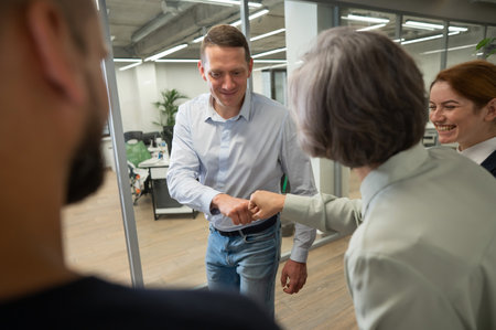 Caucasian man bumping his fists with colleagues as a sign of success.の写真素材