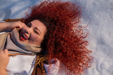 Top view of a fat red-haired woman lying on the snow.の写真素材