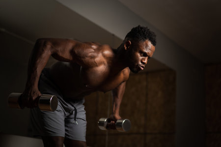 Attractive african american man doing arm exercises with dumbbells.の写真素材