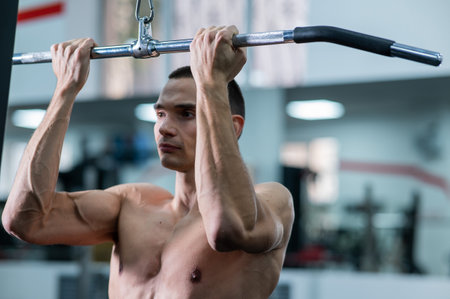 A man does a chest pulldown in the gym.