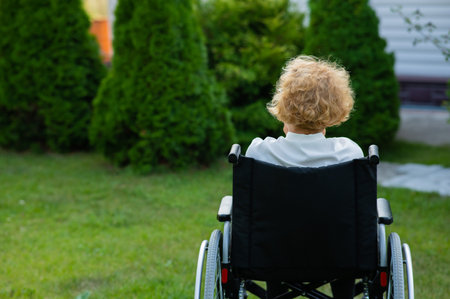 Peaceful elderly woman sitting in a wheelchair on a walk outdoors.の写真素材