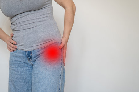Caucasian woman feels pain in her hip joint. Faceless girl holding her hands hip.の写真素材