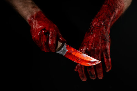 Man holding knife with bloody hand on black background.の写真素材