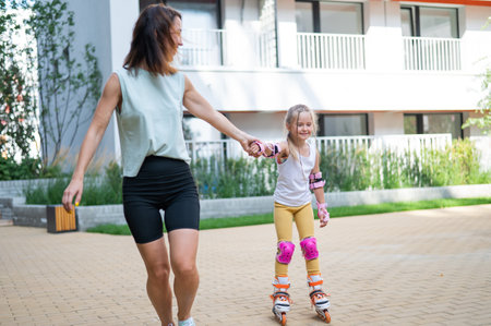 Mother helps daughter learn to roller skate.の写真素材