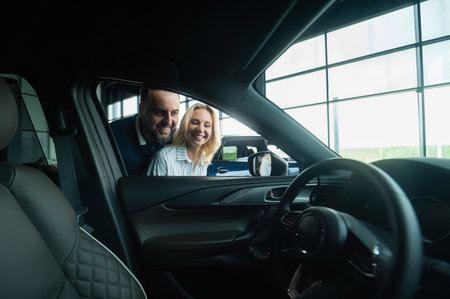 Caucasian family couple looking out the car window in a car dealership.の写真素材