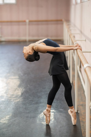 Asian woman doing back flexibility exercises at the ballet barre.の写真素材