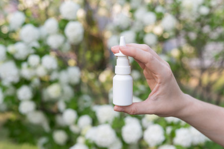 Womans hand with a nasal spray on a background of a flowering tree.の写真素材