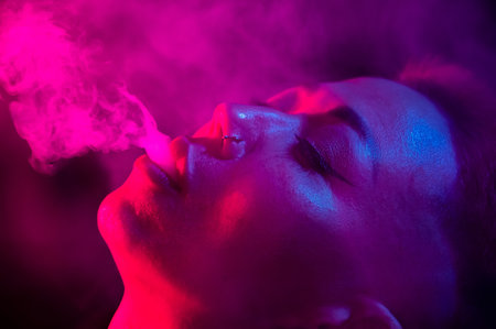 Asian woman with short haircut smoking in neon light. close-up portrait.の写真素材