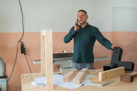 Portrait of a Caucasian man talking on the phone in a workshop.の写真素材