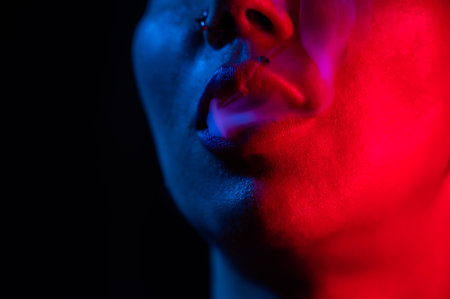 Asian woman with short haircut smoking in neon light. close-up portrait.の写真素材