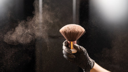 A woman shakes a large powder brush with clouds of dust on a black background. Treatment after...