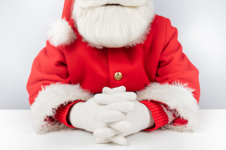 Portrait of santa claus sitting with his arms folded at a white table.の写真素材