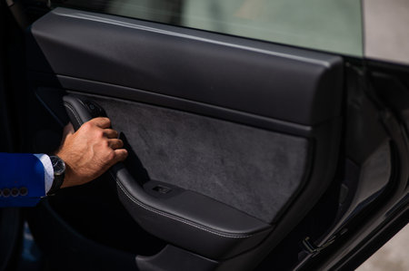 A man in a blue suit opens the car door. Close-up of a mans hand with an expensive watch.