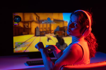 Caucasian woman asks for some more time to play computer in neon light in the dark.