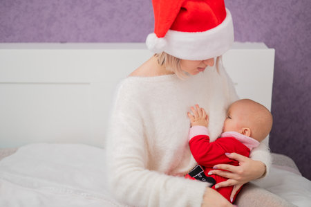 Caucasian woman breastfeeding her son in santa claus costume.の写真素材