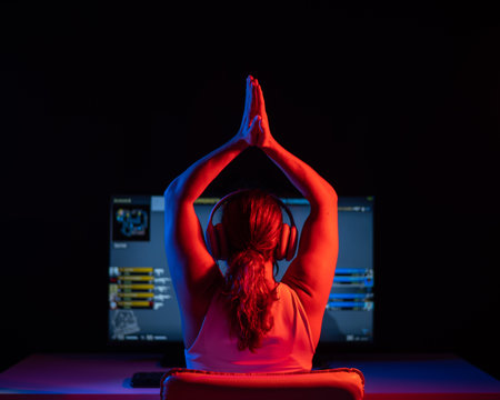 Caucasian woman rejoices at winning a computer game in neon light in the dark.の写真素材