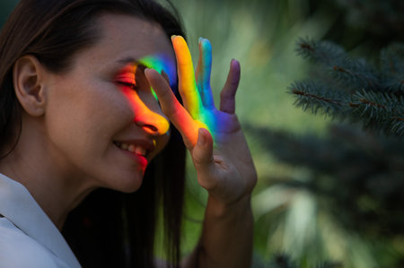 Portrait of caucasian woman with rainbow beam on her face outdoors.の写真素材