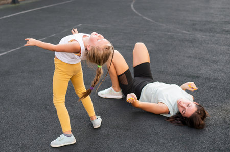 A little girl and her mom do a bridge exercise at the outdoor sports ground.の写真素材