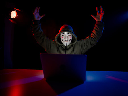 June 5, 2022 Novosibirsk, Russia: Anonymous in a hood is typing on a laptop in the dark in red blue light.のeditorial素材