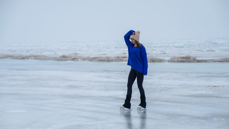 Caucasian woman in a blue sweater skating on a frozen lake.の写真素材