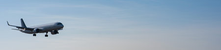Side view of an airplane landing against a blue sky. Widescreen.の写真素材
