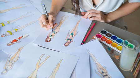 Faceless woman draws sketches of swimwear. Close-up of the hands of a fashion designer.の写真素材