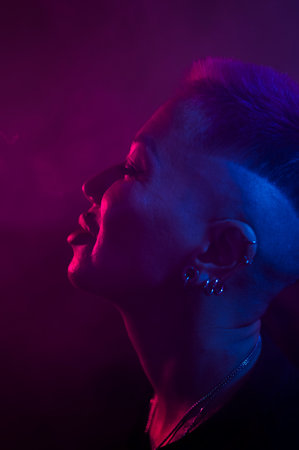 Profile Asian woman with short haircut smoking in neon light.の写真素材