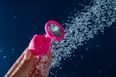 Woman washing pink anal plug under shower on blue background.の写真素材