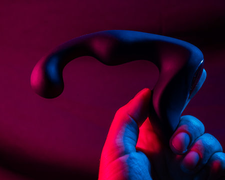 Man holding prostate stimulator in pink neon light.の写真素材