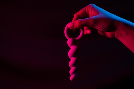 Woman holding anal beads in neon pink blue light. Copy space.の写真素材