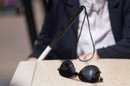 A blind woman in a business suit is sitting in an outdoor cafe.
