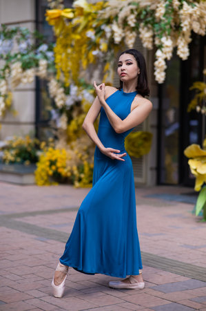 Beautiful Asian ballerina posing against the backdrop of a building decorated with flowers.の写真素材