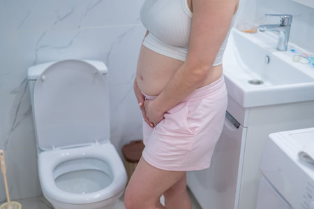 Pregnant woman holding her belly in the toilet. incontinence during pregnancy.の写真素材