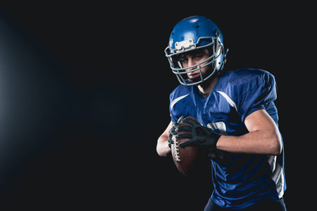 Portrait of a man in a blue uniform for american football on a black background.の写真素材