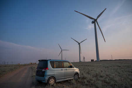 Blue car at windmills at sunset. Alternative energy source.の写真素材