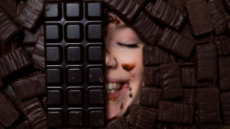 The face of a caucasian woman surrounded by sweets. The girl is smeared in chocolate.の写真素材